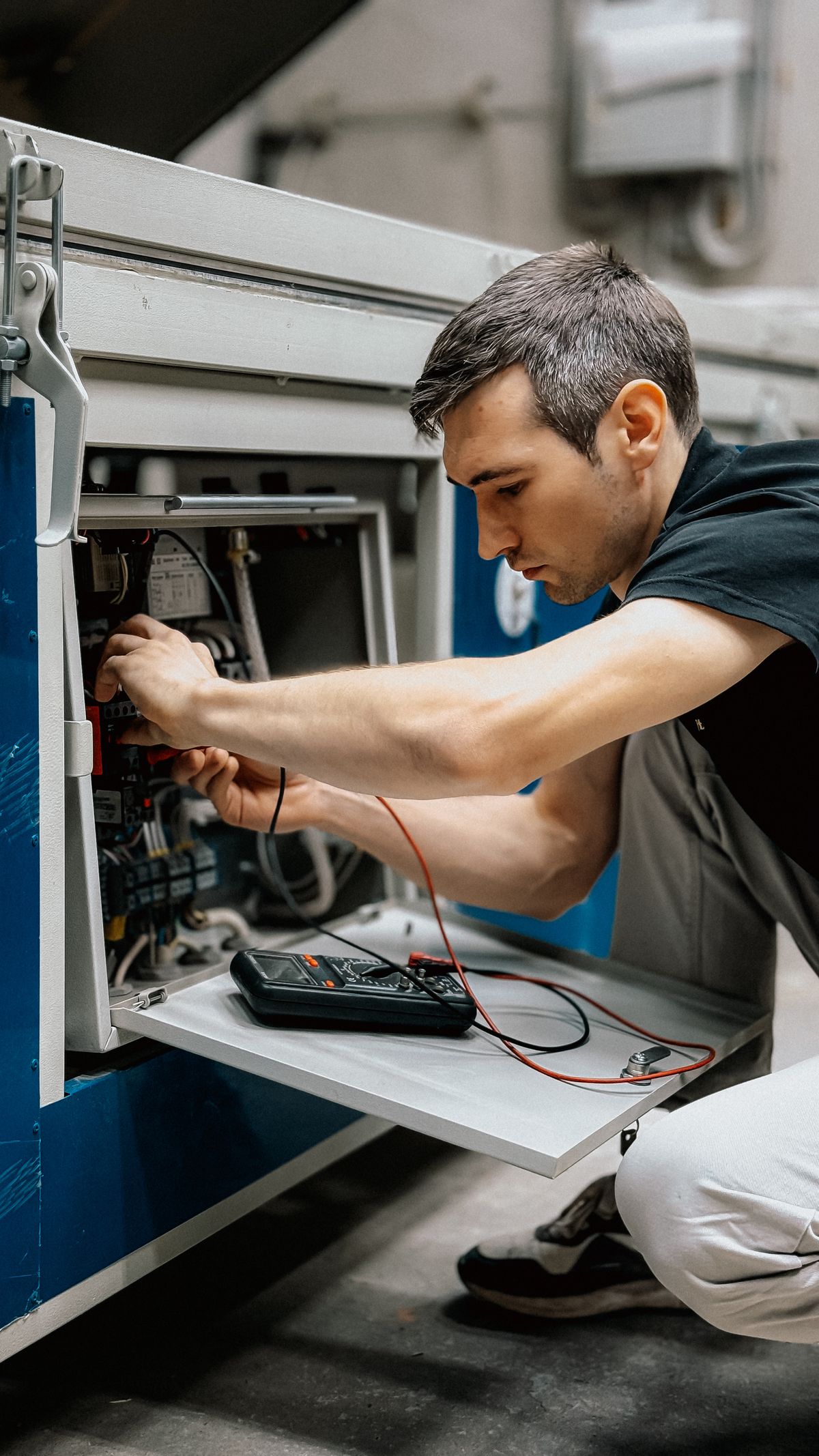 Technician taking a field reading with a multimeter on a control panel
